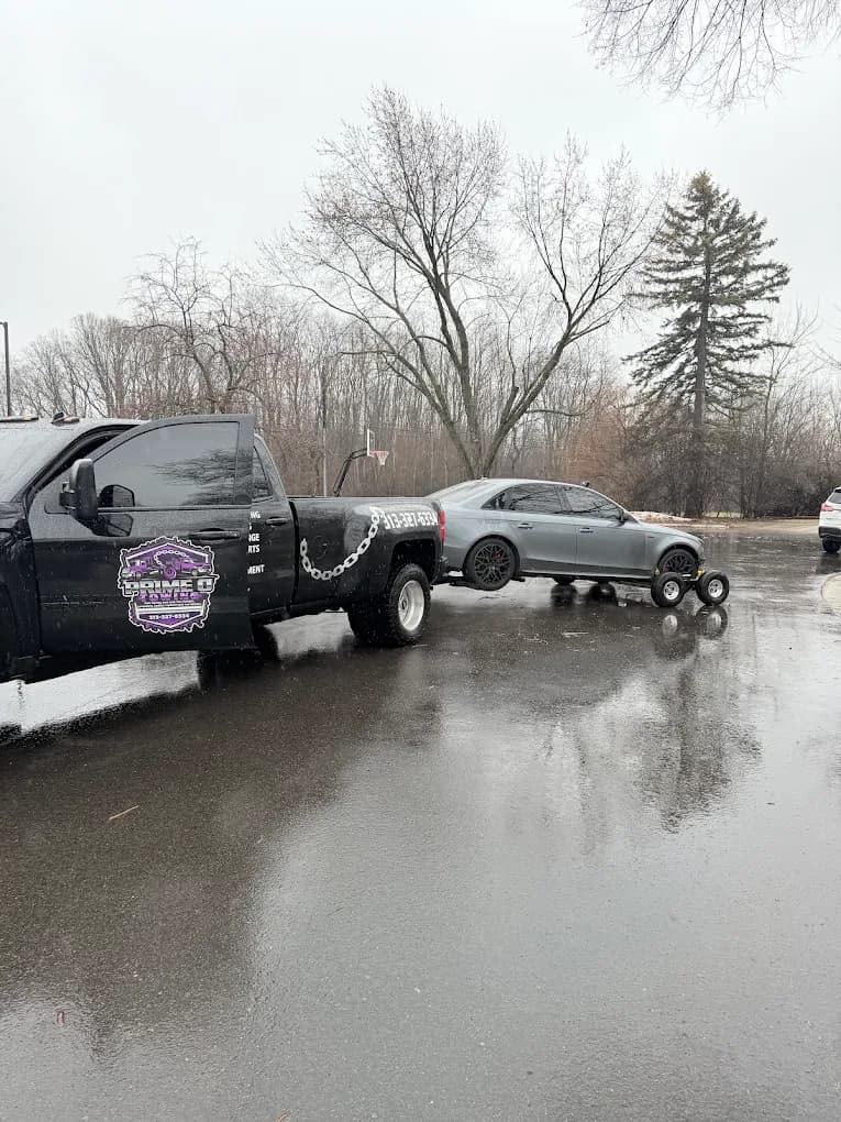 Prime O Towing wheel-lift Silverado transporting a silver sports car from a Metro Detroit parking lot